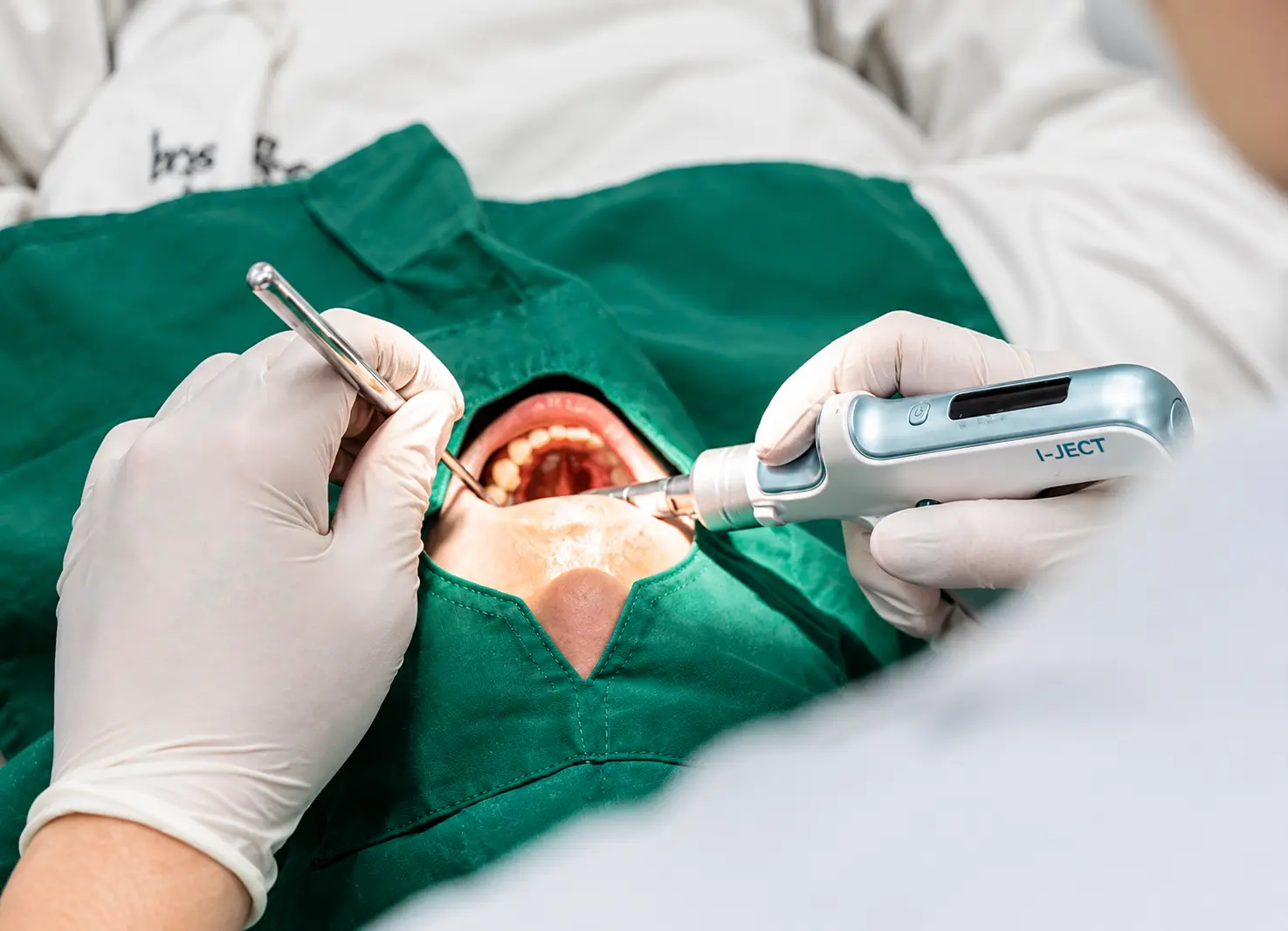 I-Ject 전동 마취기의 실제 진료 적용 러버댐을 장착한 환자의 치과 치료에서 의료진이 I-Ject 전동 마취기를 직접 사용하는 실제 진료 사진